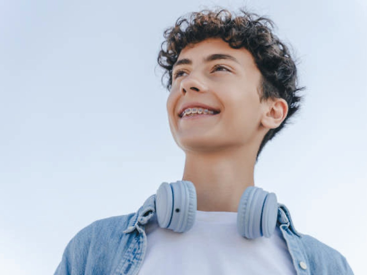 Smiling teenage boy wearing braces with headphones around his neck